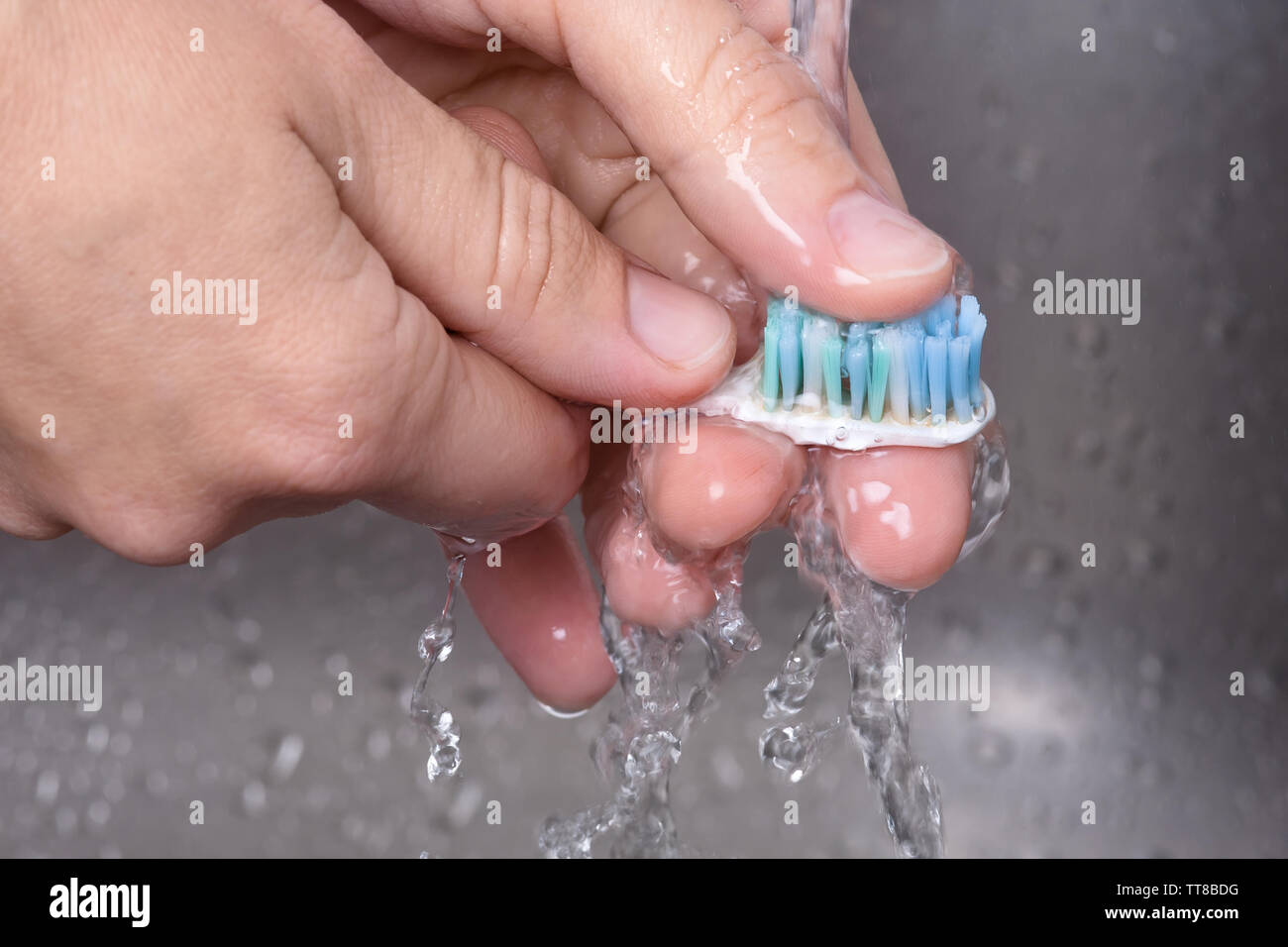 Cepillo de lavado a mano bajo un chorro de agua, closeup Foto de stock