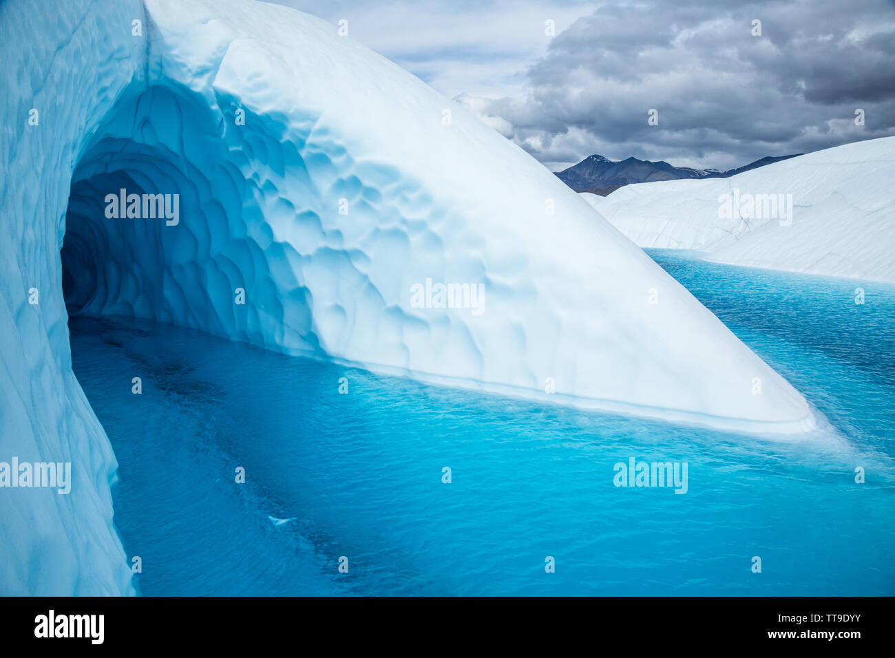Una gran entrada a la cueva de hielo en el Glaciar Matanuska. La cueva está inundado con agua proveniente de la fusión del hielo del glaciar. Foto de stock