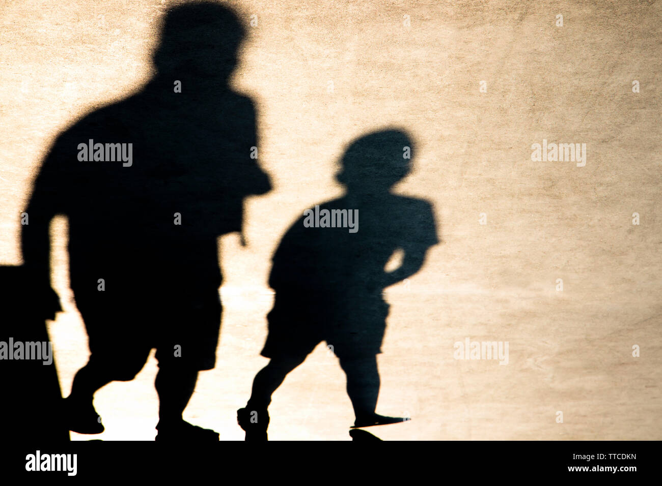 Borrosa sombra de un niño y un adulto caminando en Sunset Foto de stock