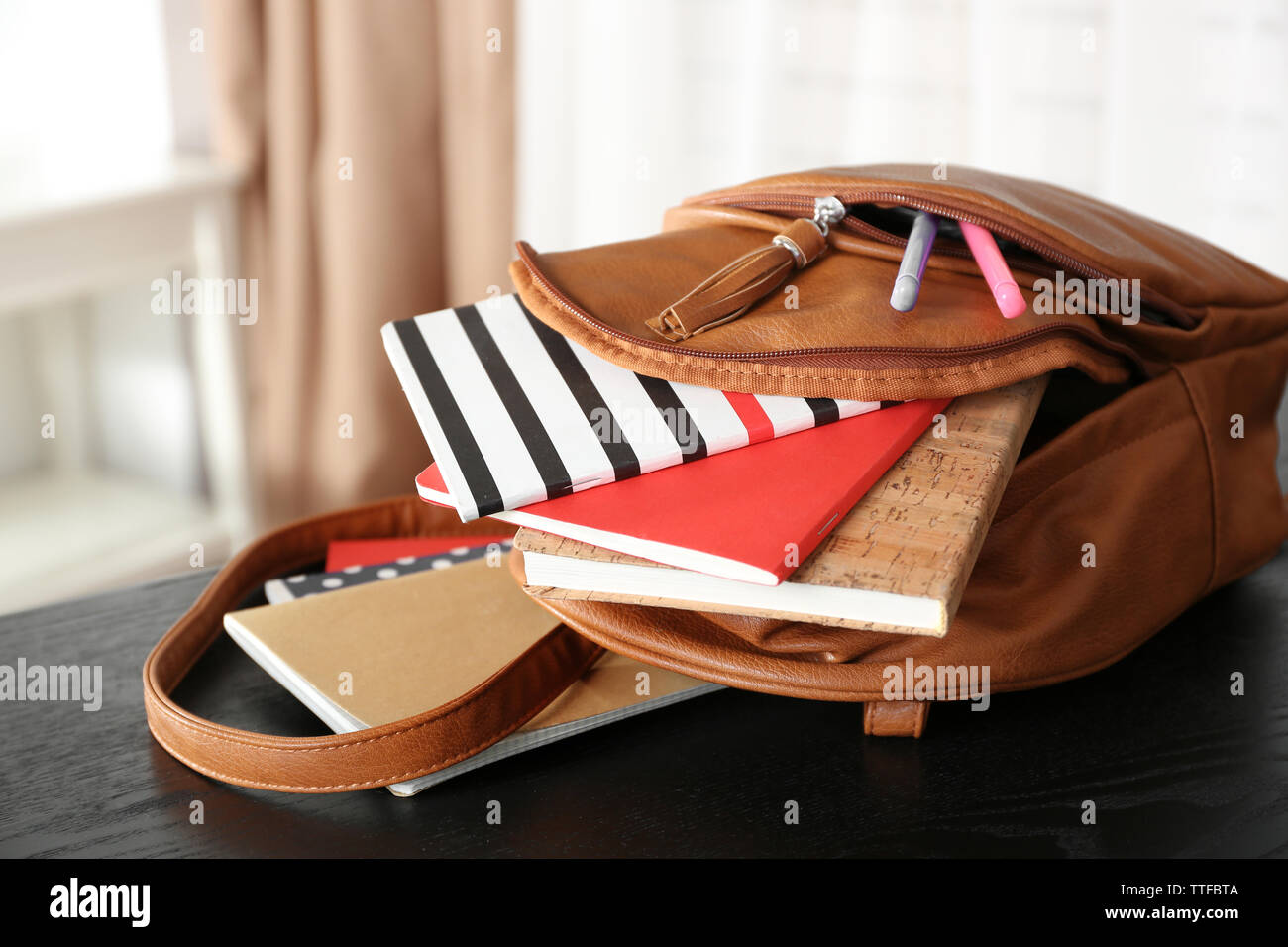 Mochila de cuero marrón con cuadernos y lápices en la mesa de madera en  interiores Fotografía de stock - Alamy