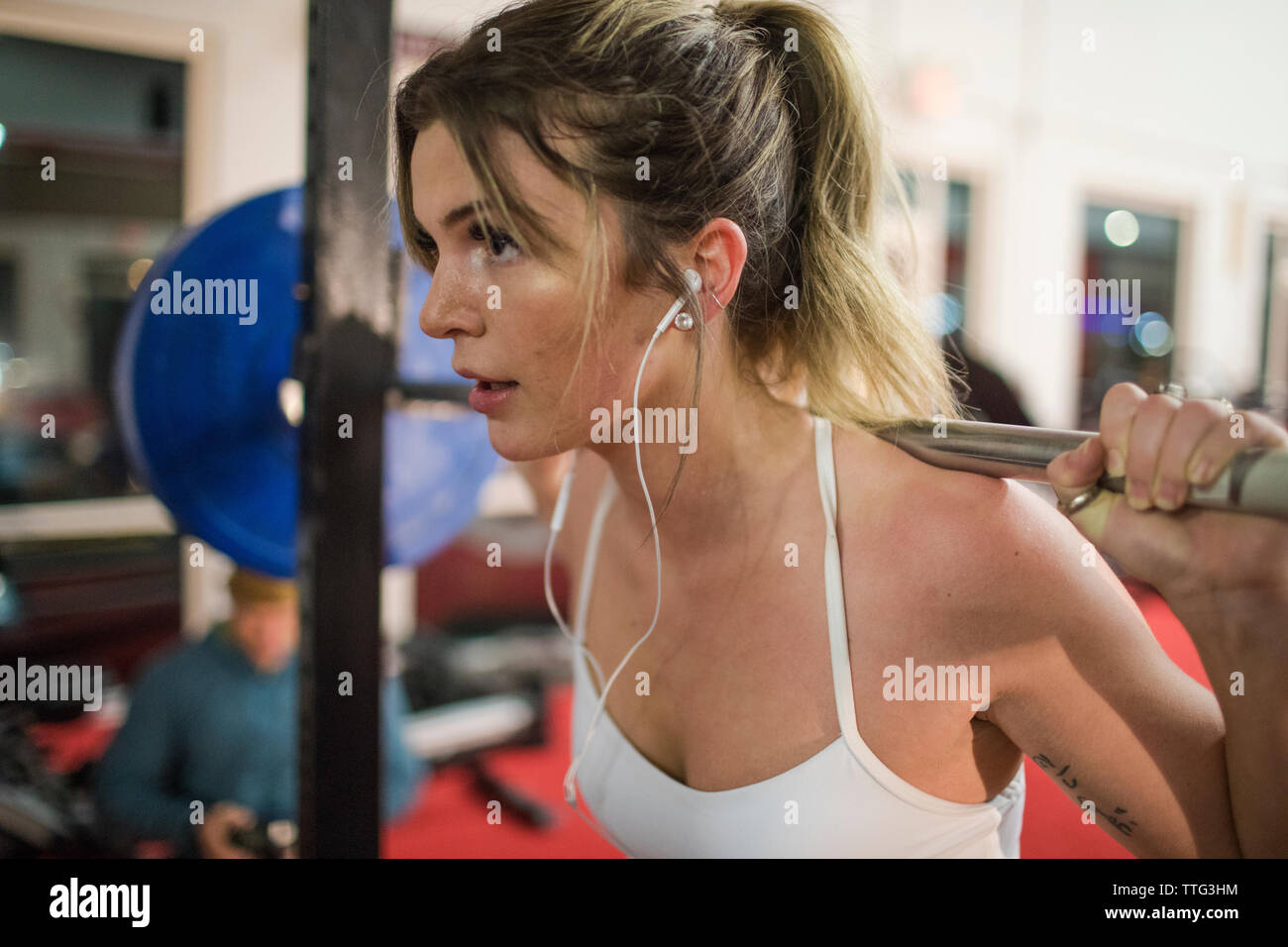 Vista recortada de mujer atractiva levantamiento barbell en gimnasio Foto de stock