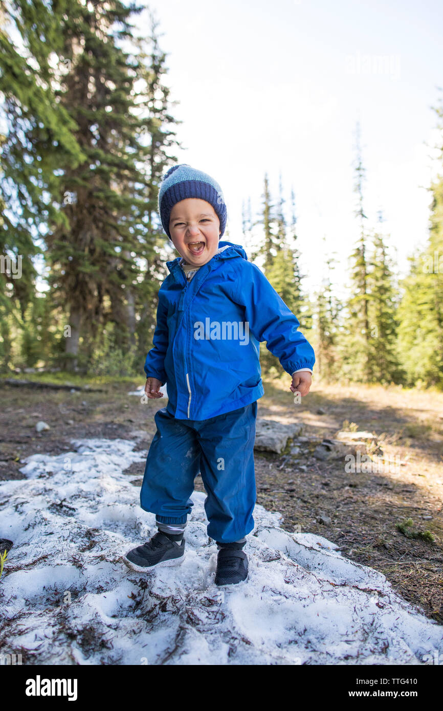 Entusiasmado niño chico jugando en un parche de nieve. Foto de stock