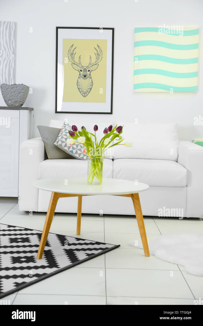 Salón Moderno interior blanco con sofá, mesa de café, grandes gráficos y  lienzos de alfombras en la pared blanca Fotografía de stock - Alamy