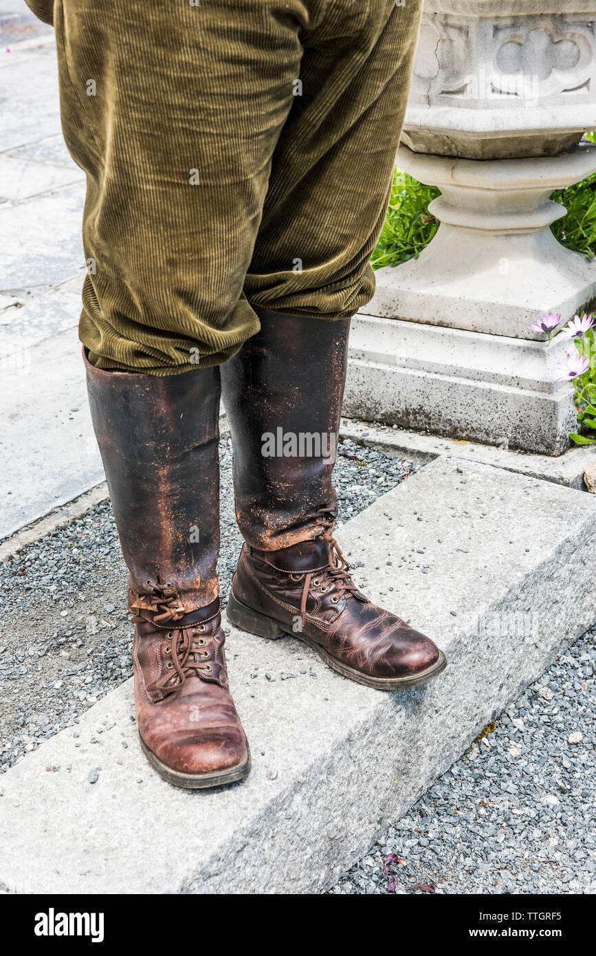 Fuelles de cuero bien gastado y botas y pantalones de pana desgastada por un trabajador de granja. Foto de stock