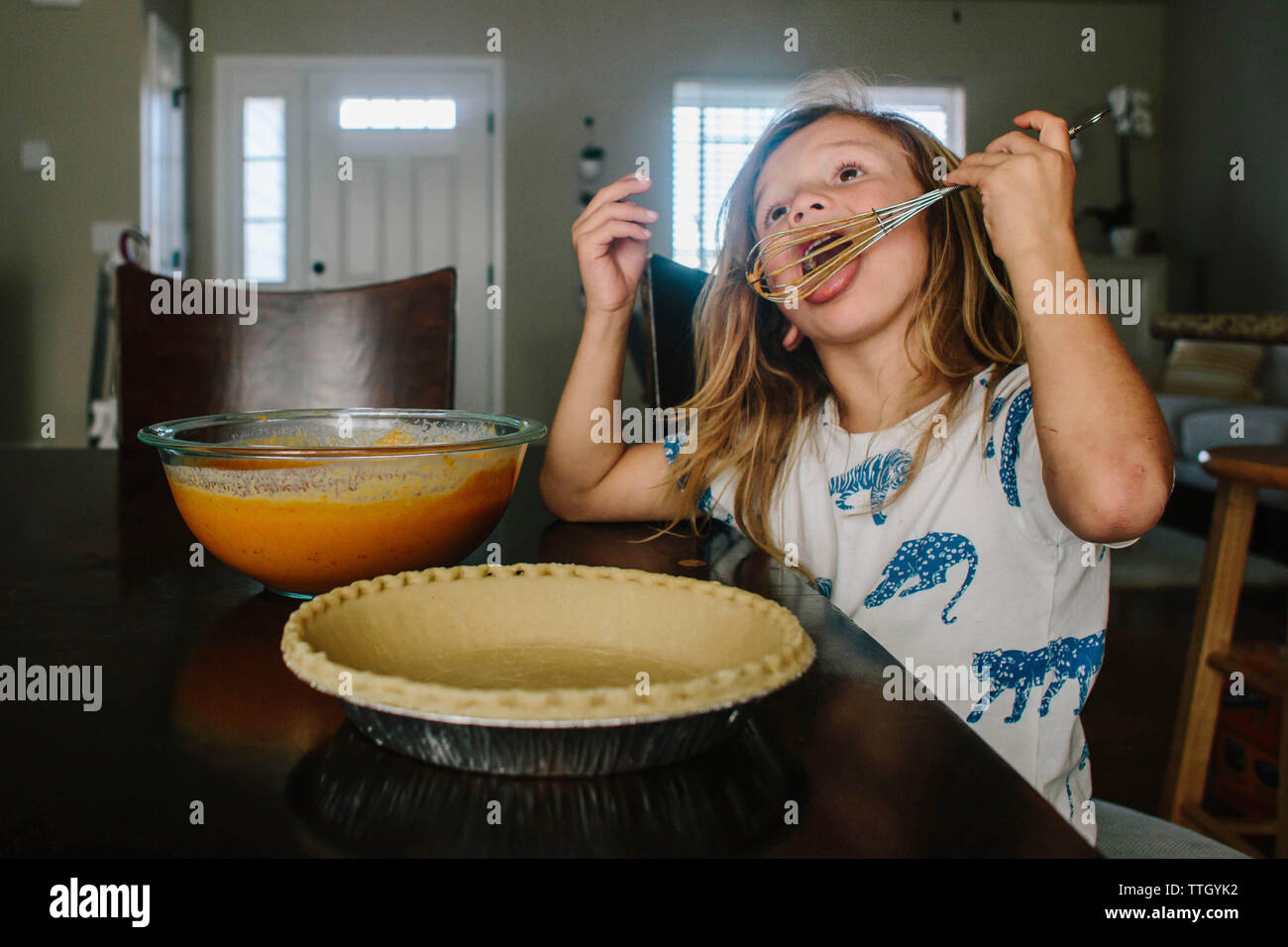 Chica lamer bigote sentado preparando la tarta en casa Foto de stock