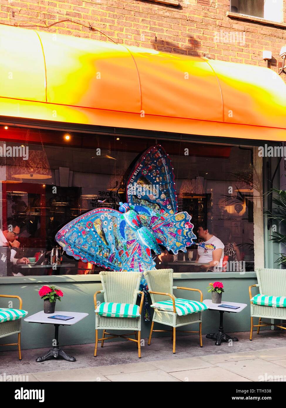 Sillas fuera de una cafetería con una mariposa en el cristal Fotografía de  stock - Alamy