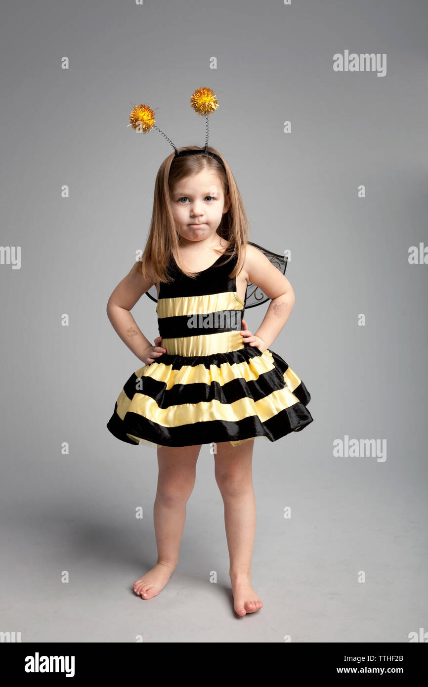 Retrato de niña vestidos de traje de abeja mientras está de pie contra el  fondo gris Fotografía de stock - Alamy