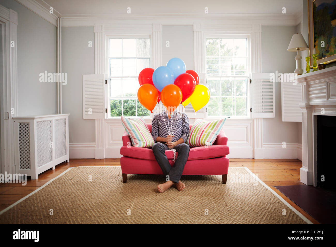 Hombre sujetando globos de helio, mientras están sentados en un sofá en casa Foto de stock