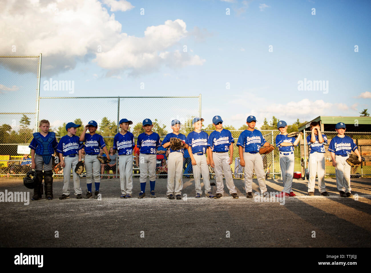 El equipo de béisbol de pie en campo contra el cielo Foto de stock