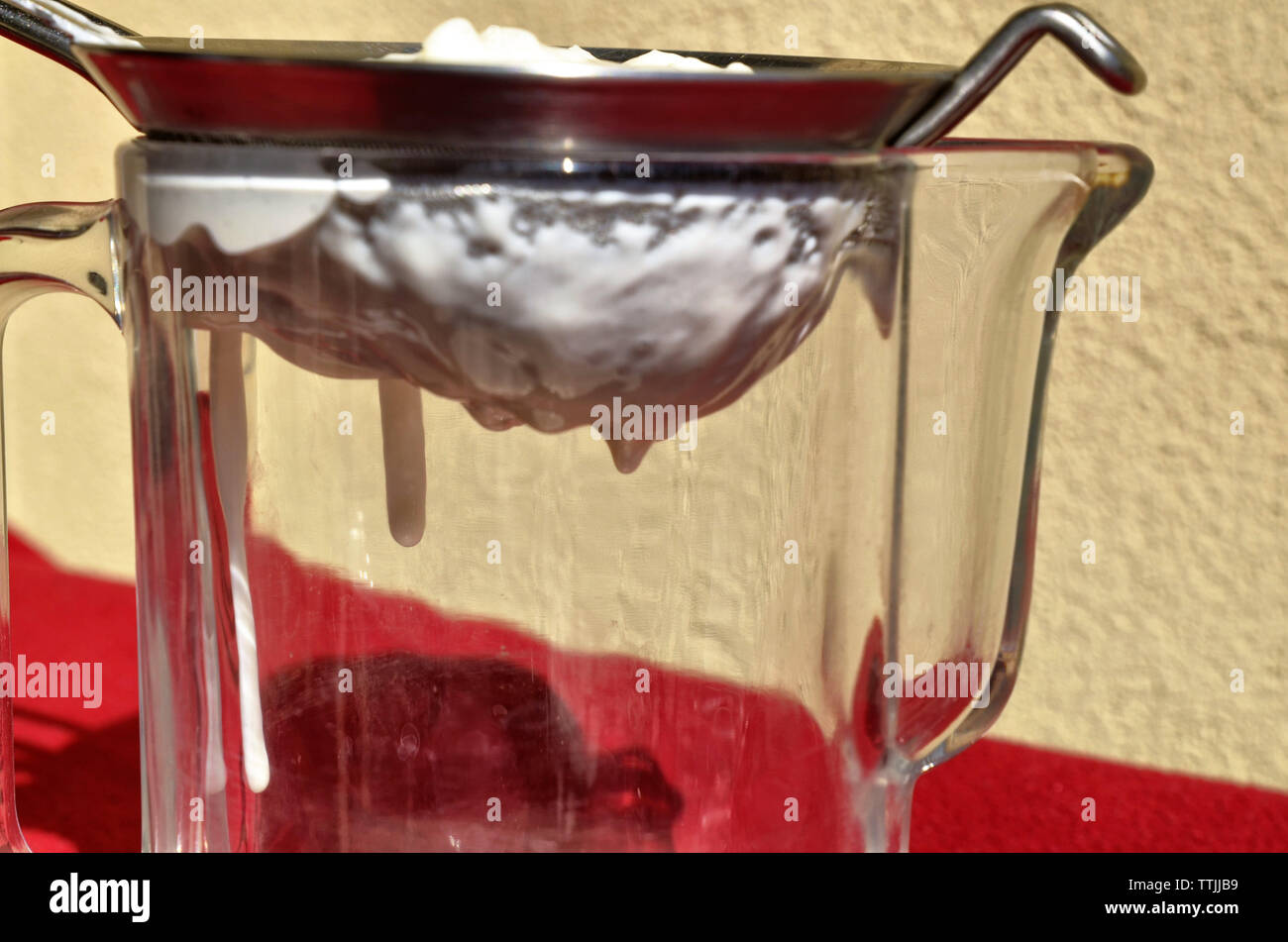 Kefir filtrar con un colador de red. A través de la jarra de cristal es  posible ver el blanco cremoso líquido que fluye Fotografía de stock - Alamy