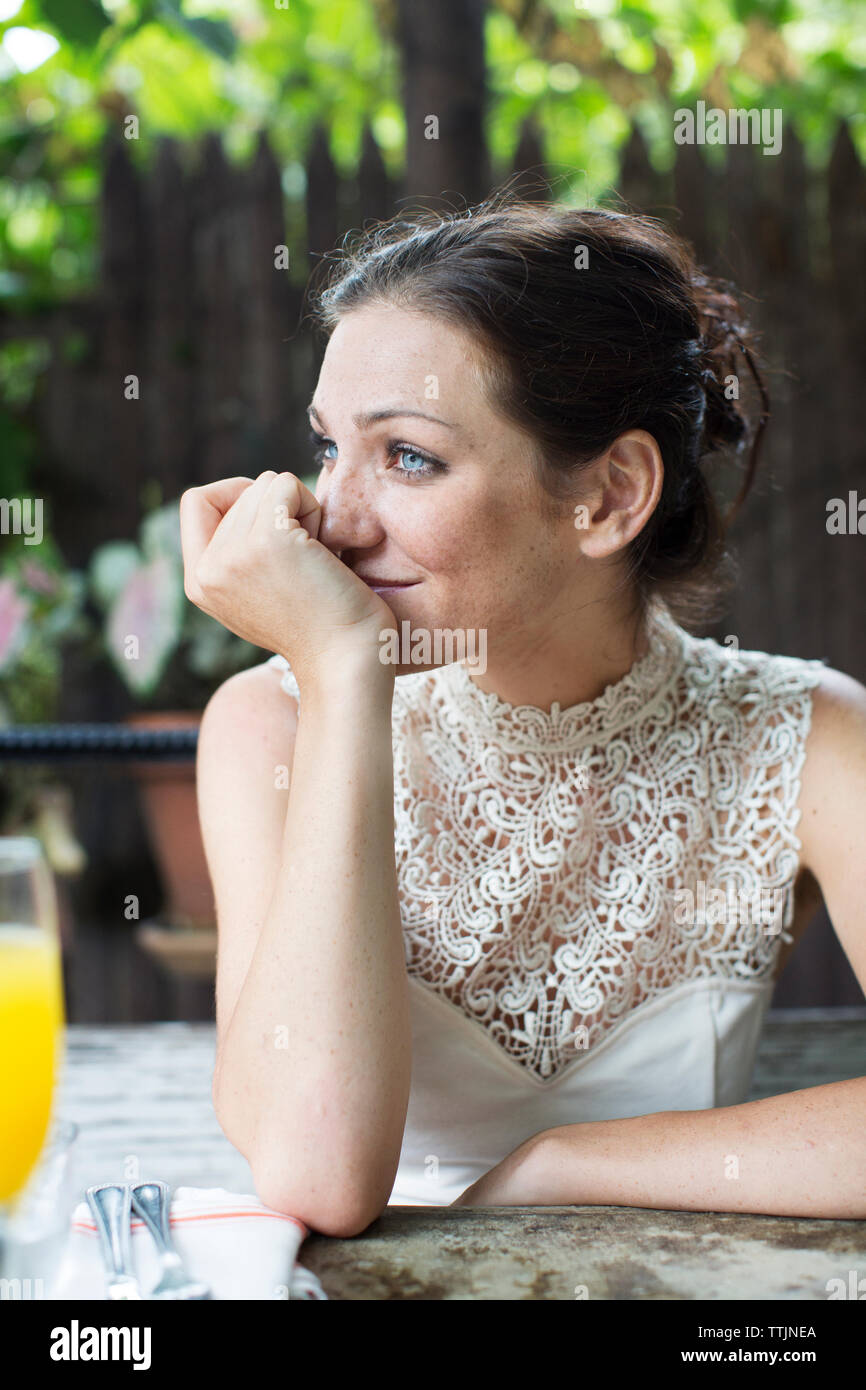 Mujer con la mano en el mentón mirando a otro lado mientras está sentado en un restaurante Foto de stock