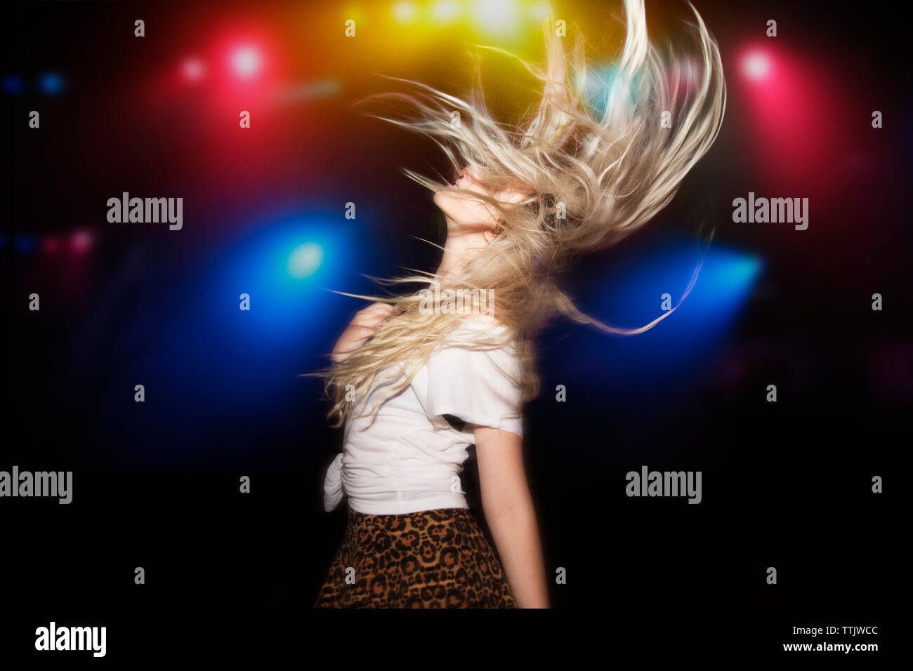 Mujer con cabello deslucido bailando contra encendido luces multicolores en garden party Foto de stock