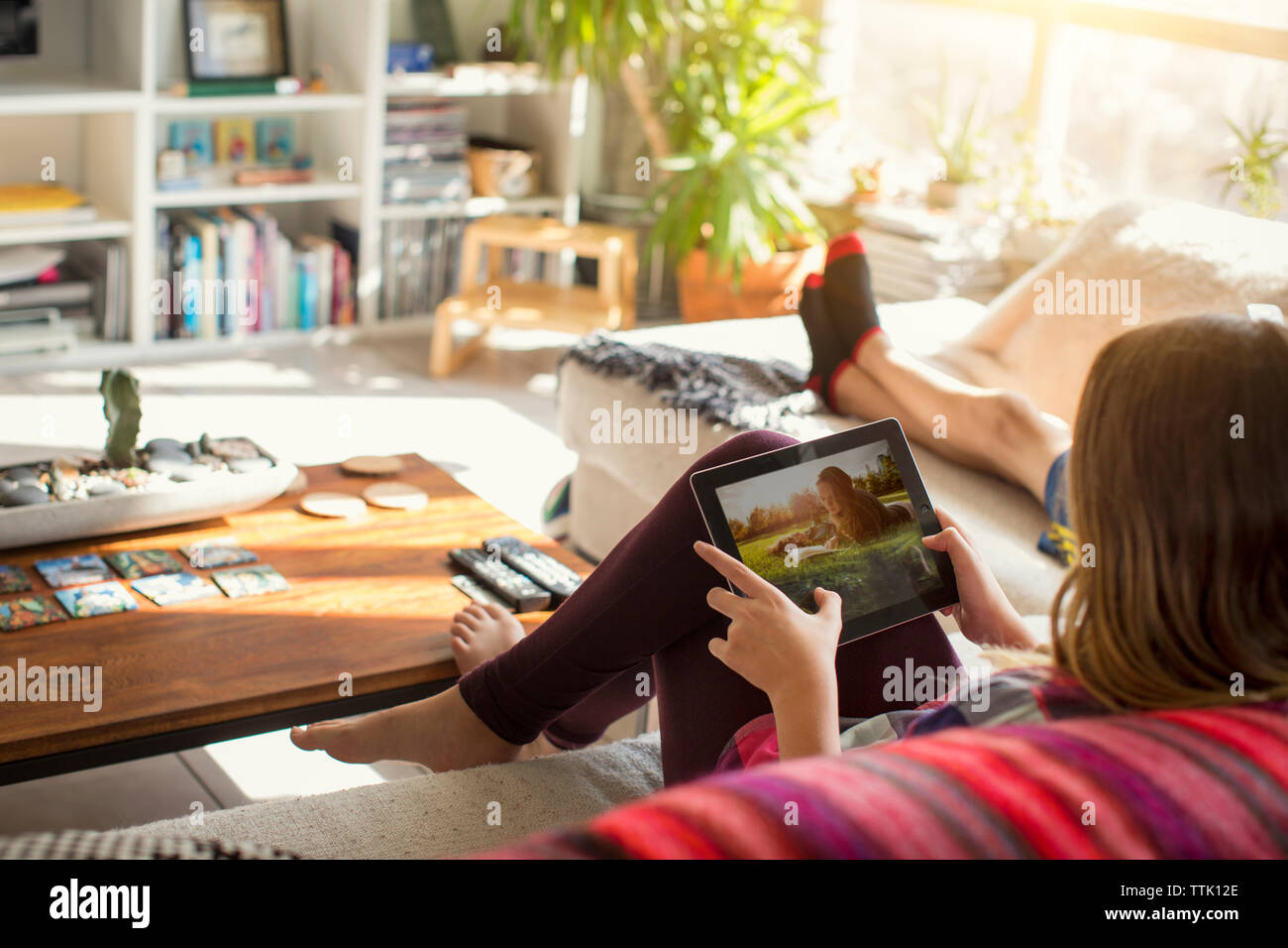 Chica busca imágenes en Tablet PC mientras está sentado en el sofá Foto de stock
