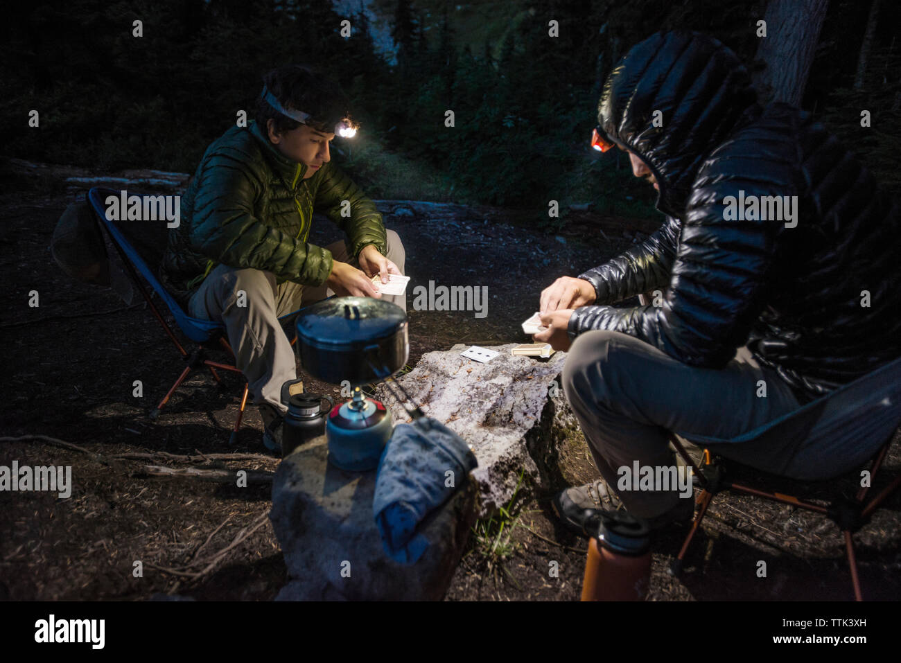 Amigos juego de naipes en el camping en el bosque al atardecer Foto de stock