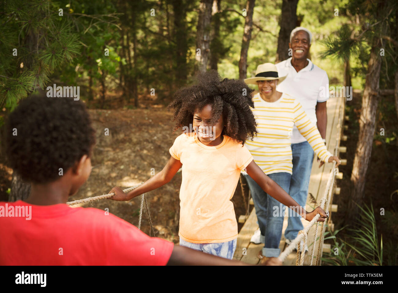 Familia Feliz caminar sobre la pasarela en el bosque Foto de stock