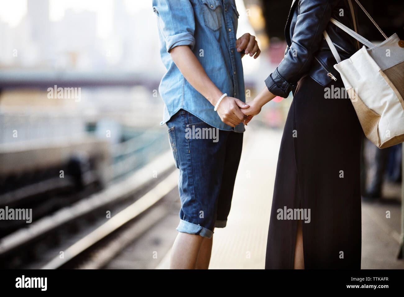 Sección media de la pareja de pie con las manos en la ciudad Foto de stock