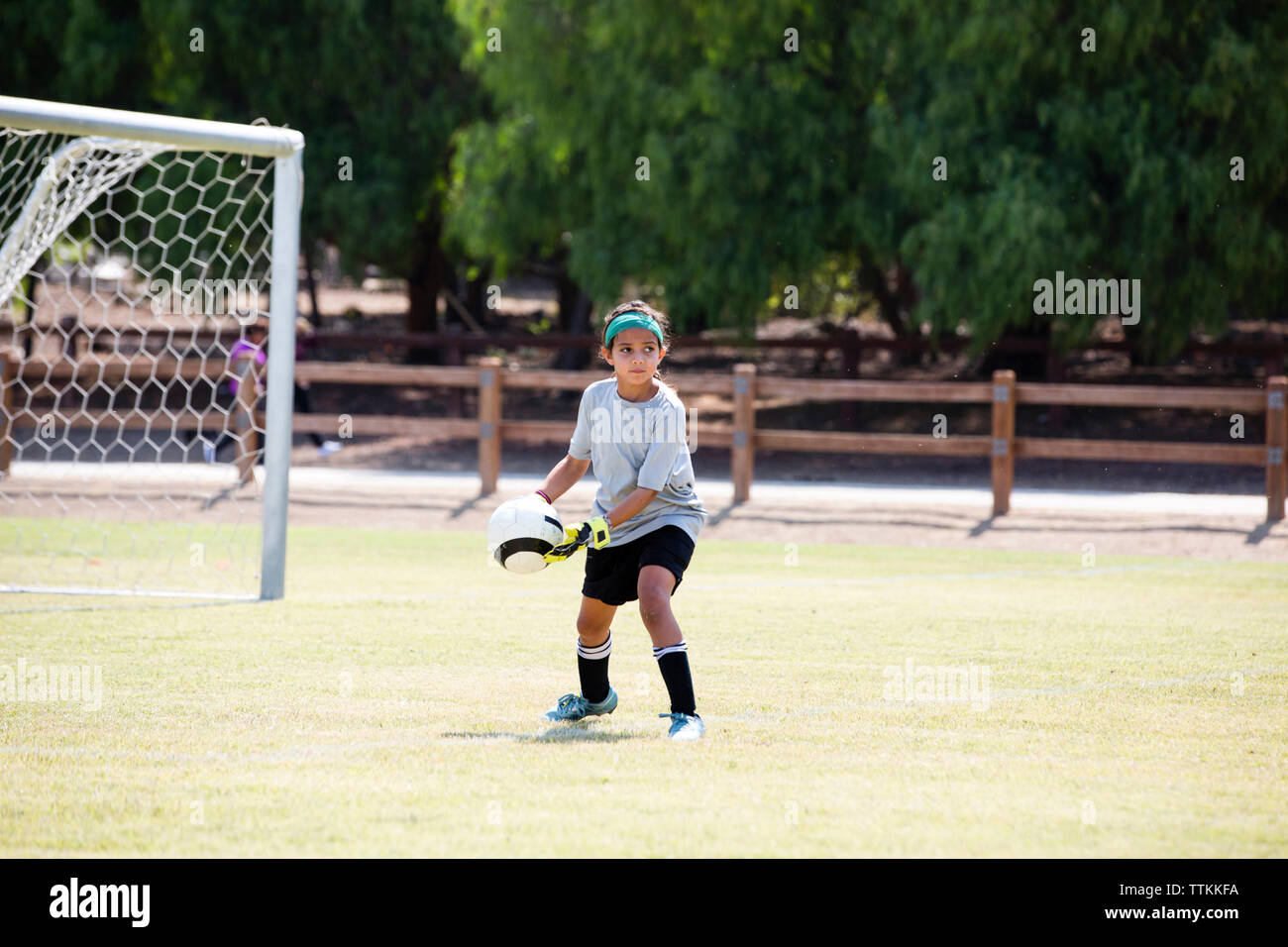 Chica que practica el fútbol en el patio de recreo Foto de stock
