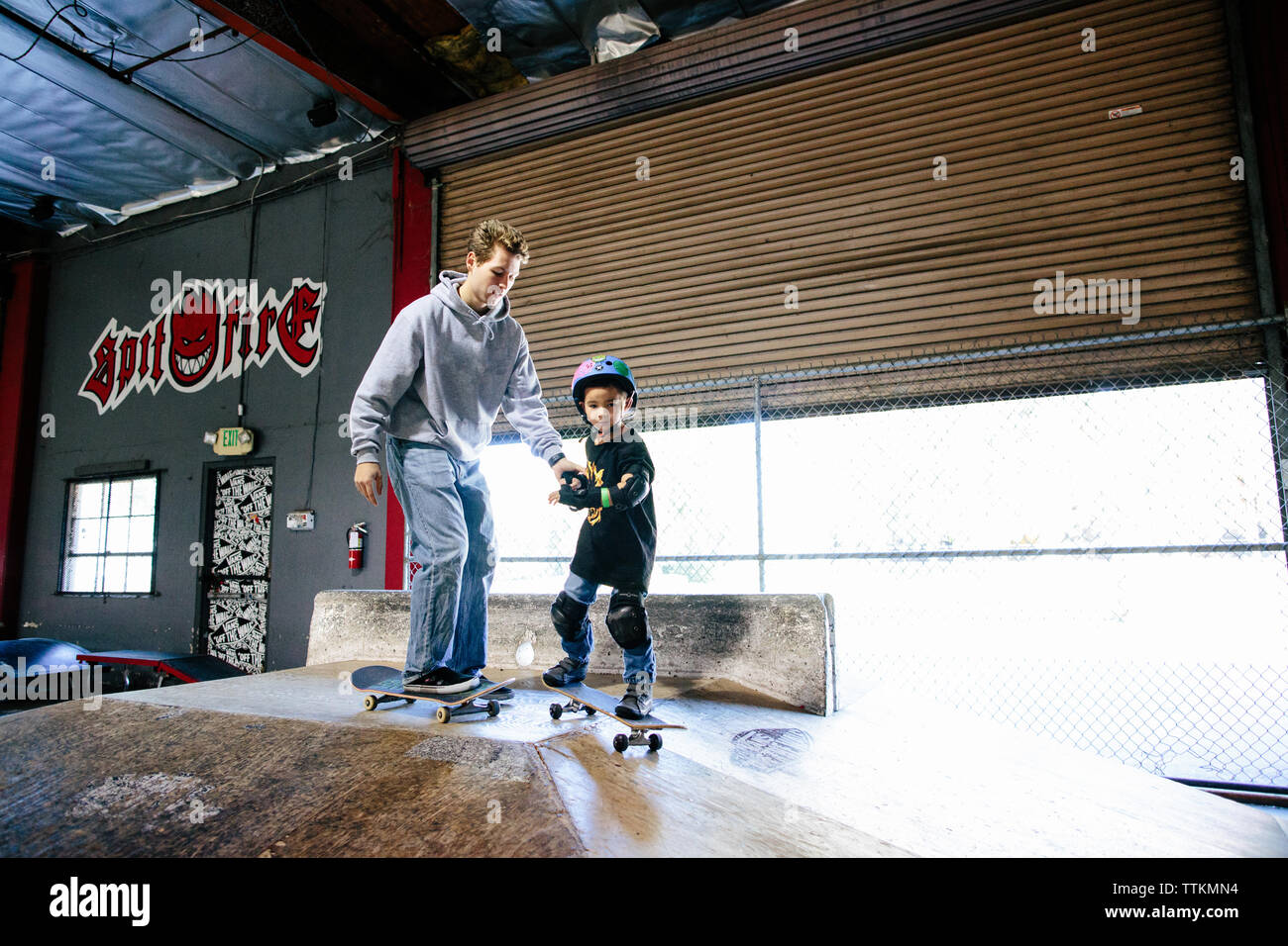 El cabrito y el patinador skateboarding instructor se preparan para ir hacia abajo una rampa Foto de stock