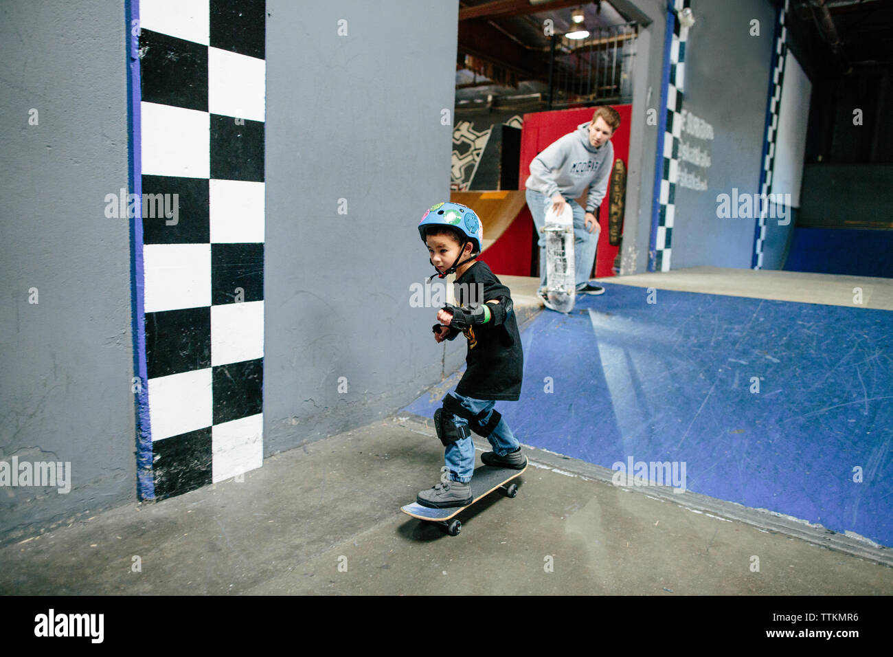 Skater kid parece enfocarse después de bajar la rampa de patinaje, instructor relojes Foto de stock