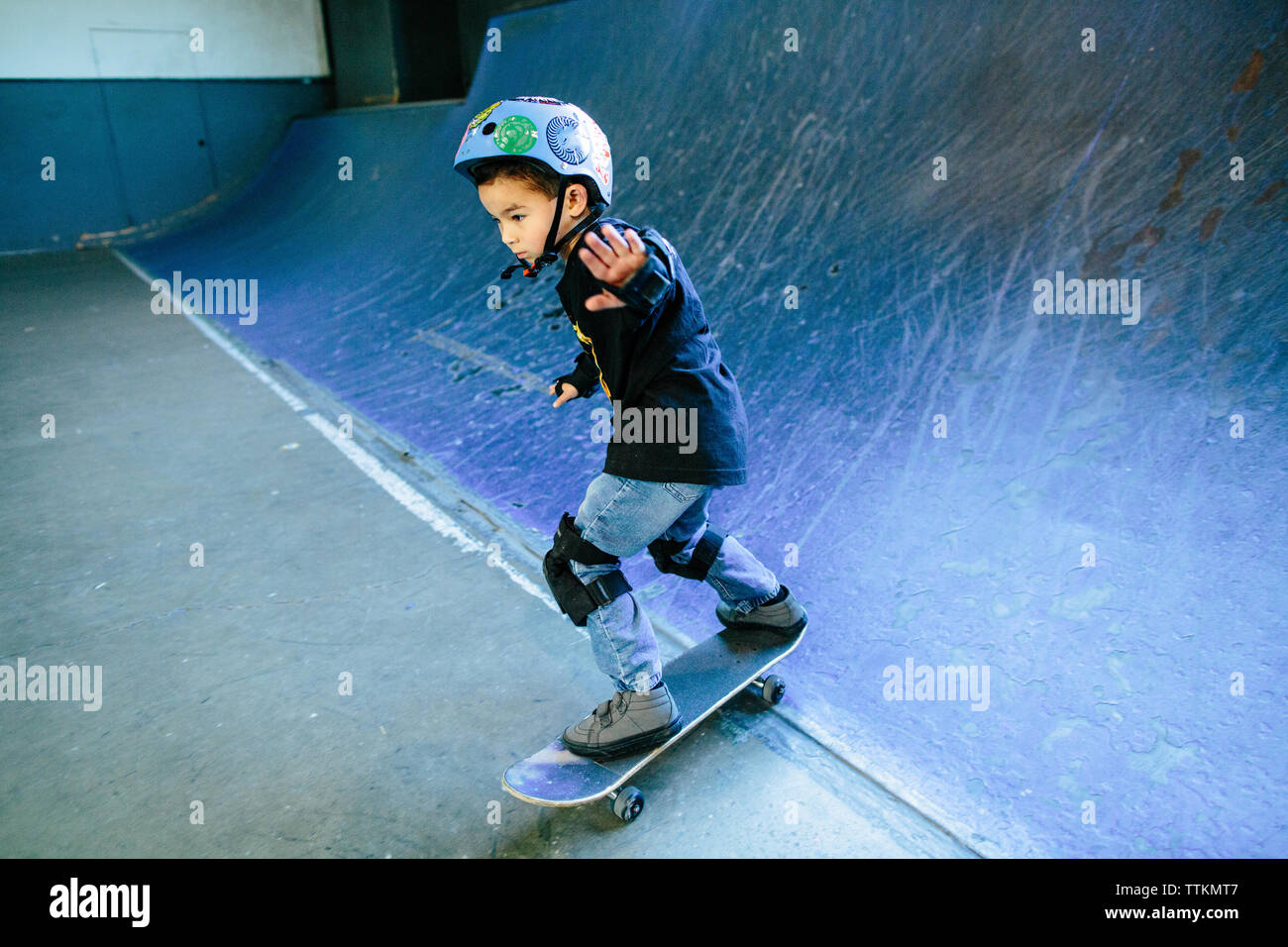 Patinador de skateboard kid abajo una rampa azul Foto de stock