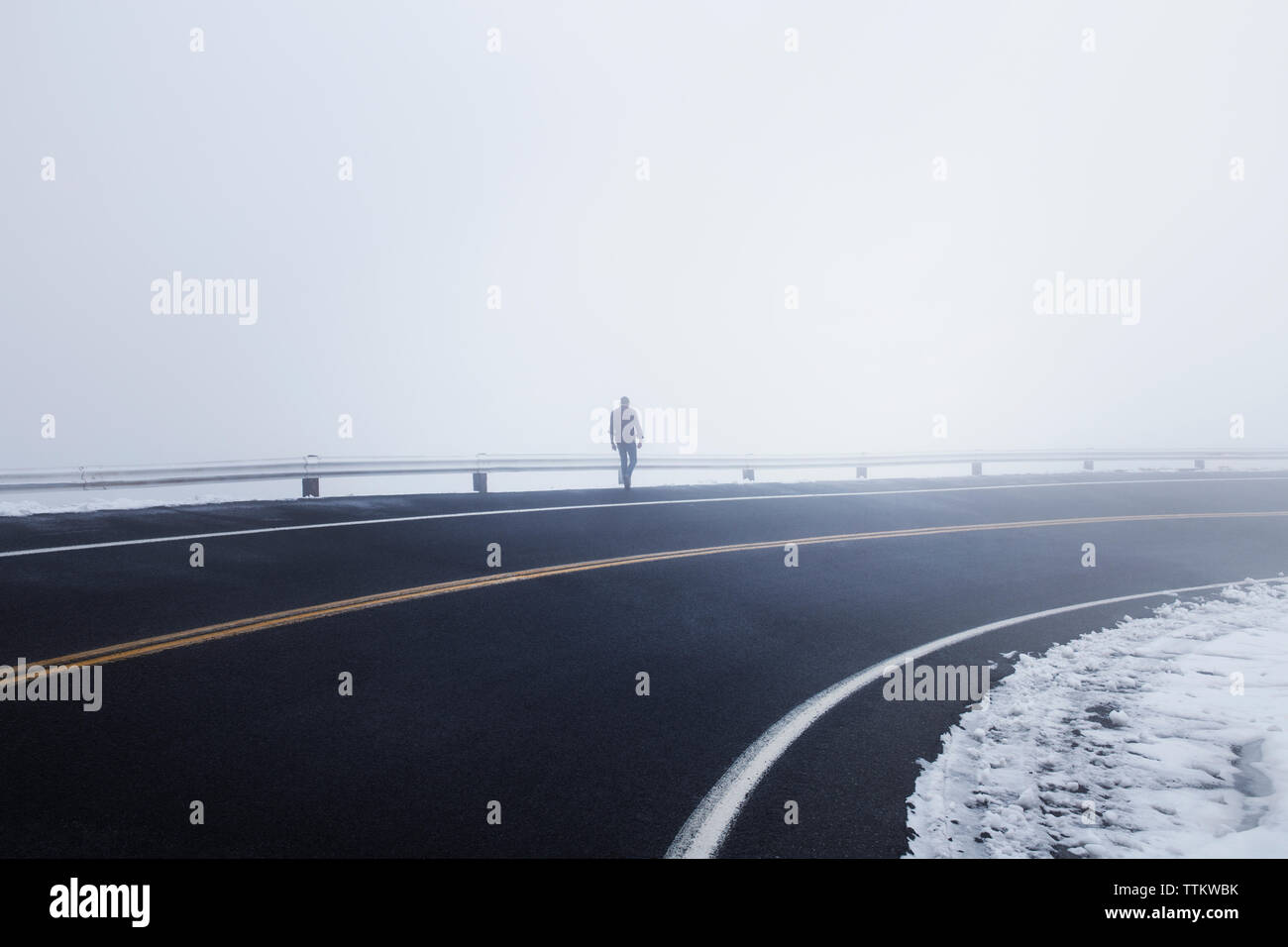 Hombre caminando por la autopista durante la niebla Foto de stock