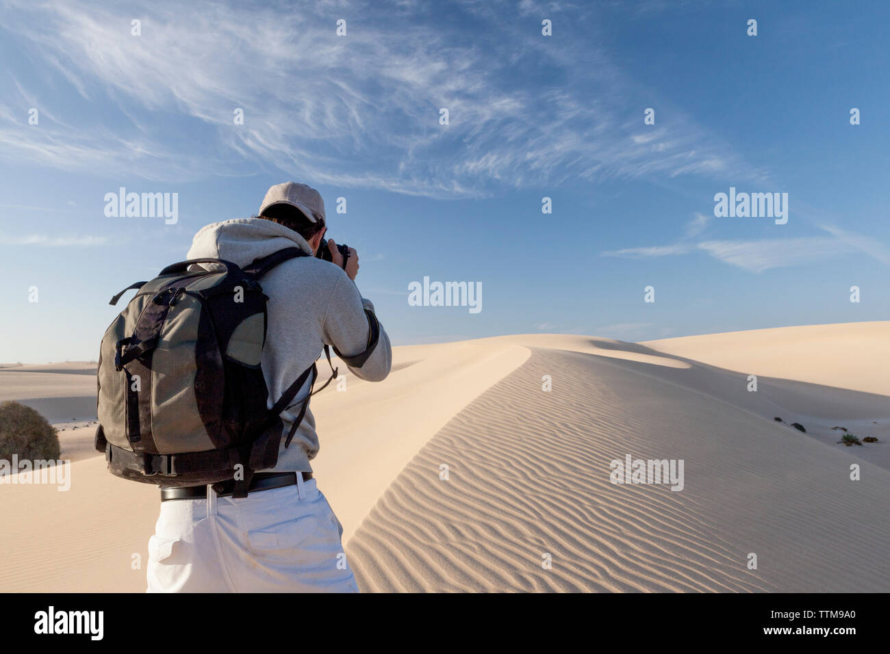 Entre 20 y 30 años de edad fotógrafo tomando fotos de dunas de arena de la isla de Fuerteventura. Foto de stock