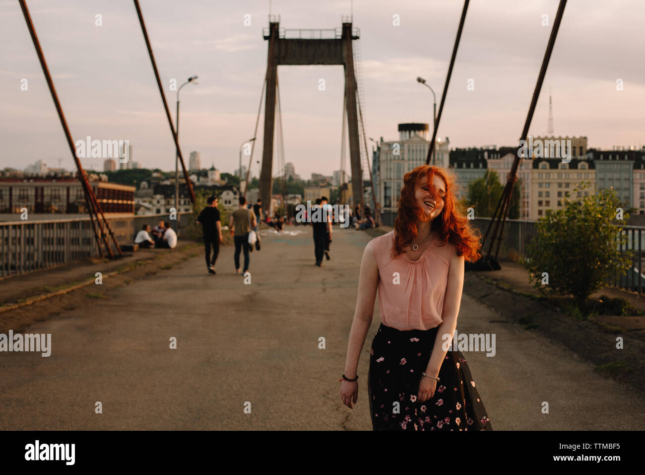 Joven mujer alegre caminando sobre el puente en la ciudad Foto de stock