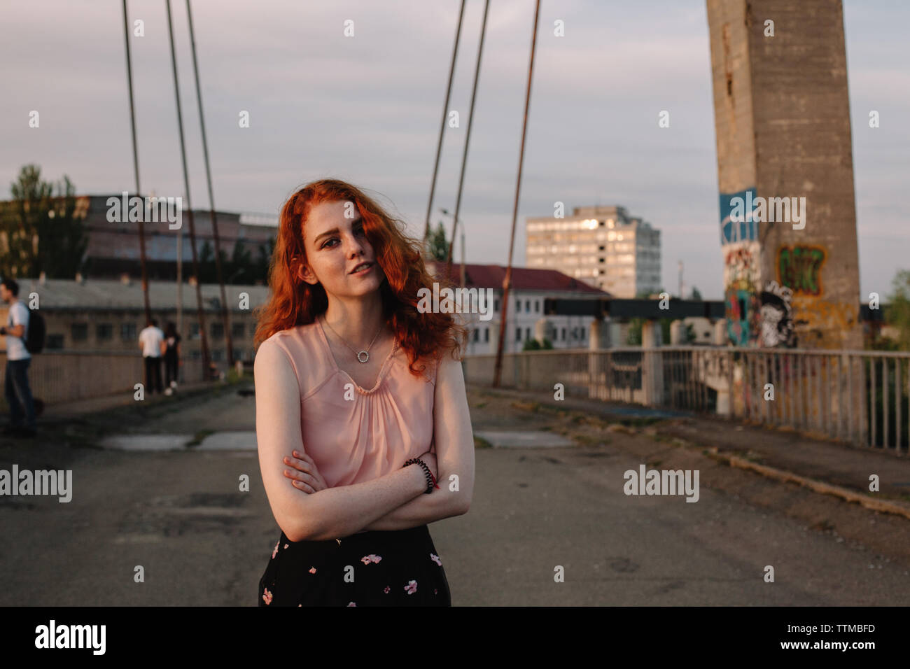 Retrato de mujer joven con el pelo rojo de pie en el puente en la ciudad Foto de stock