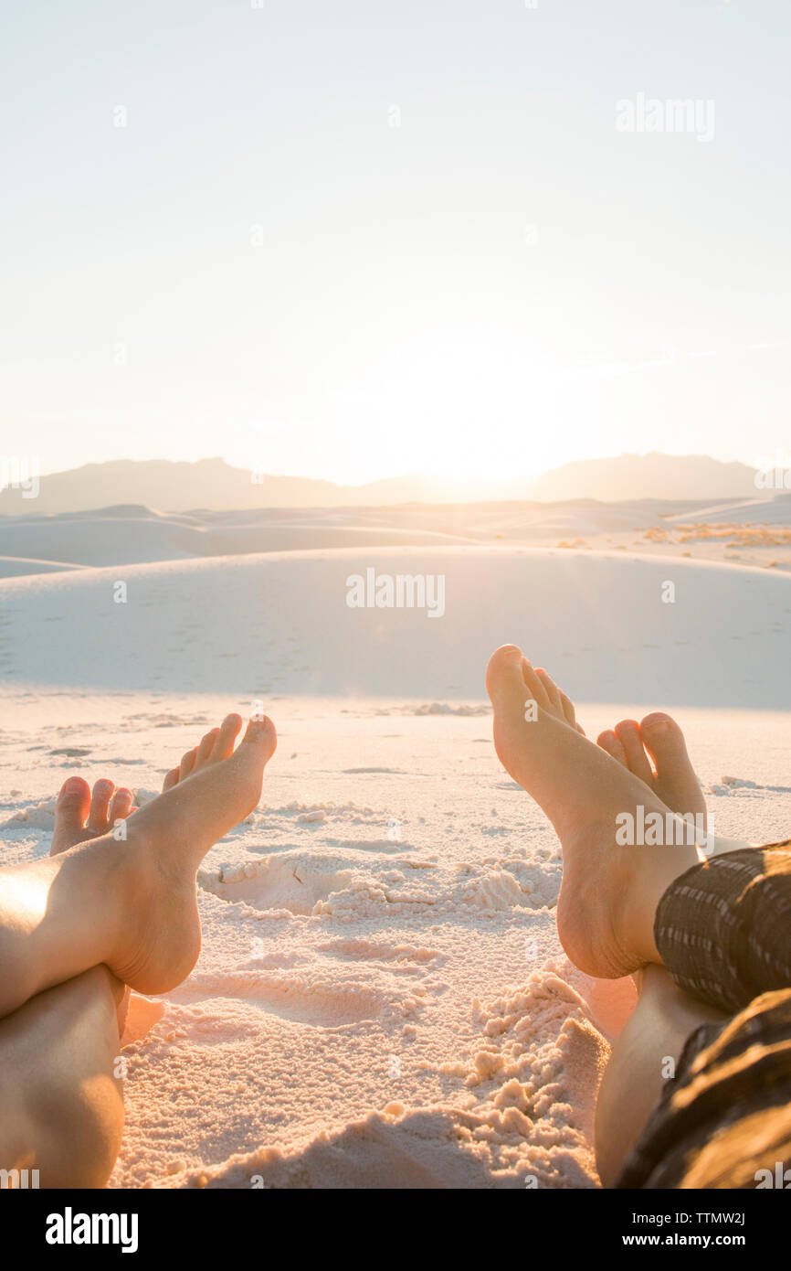Bajo la sección de amigos sentados en el White Sands National Monument en contra de cielo despejado durante el día soleado Foto de stock