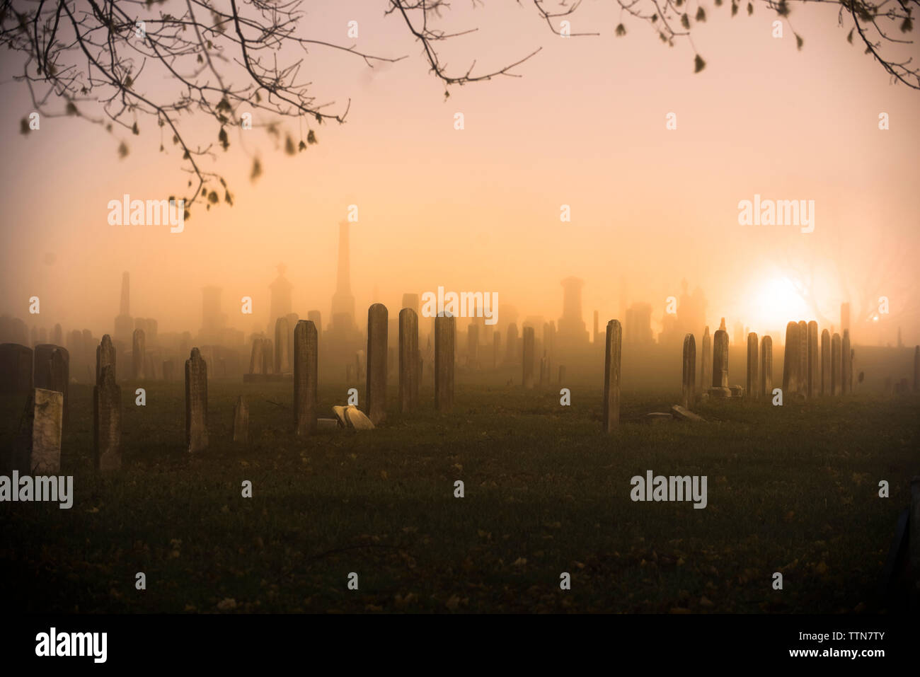 Lápida en el cementerio de silueta contra el cielo durante la puesta de sol Foto de stock