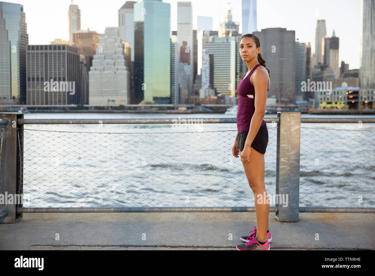 Retrato de la atleta femenina de pie en el paseo por el río Foto de stock