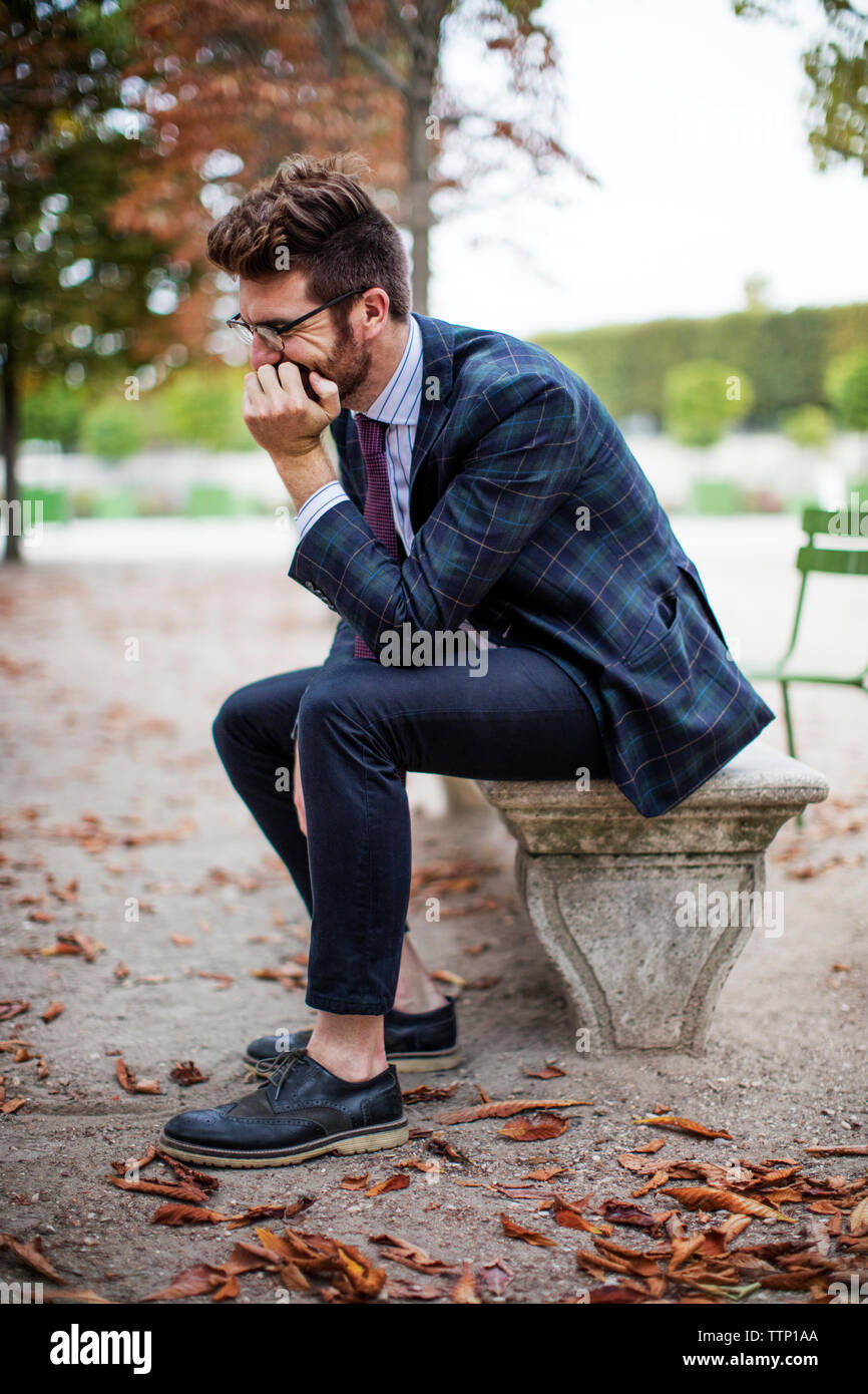 Pensativo empresario sentado en un banco del parque durante el otoño Foto de stock