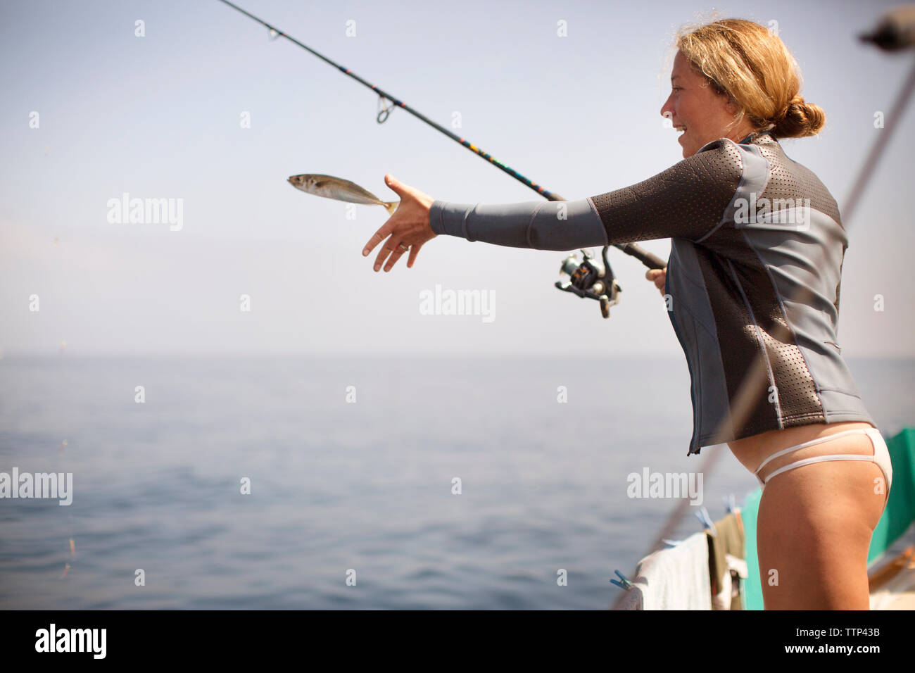 Mujer alegre y liberar peces mientras está parado en la orilla Foto de stock