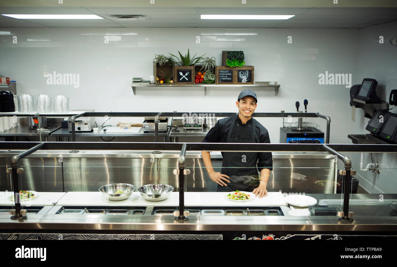 Retrato sonriente permanente chef en cocina comercial Foto de stock