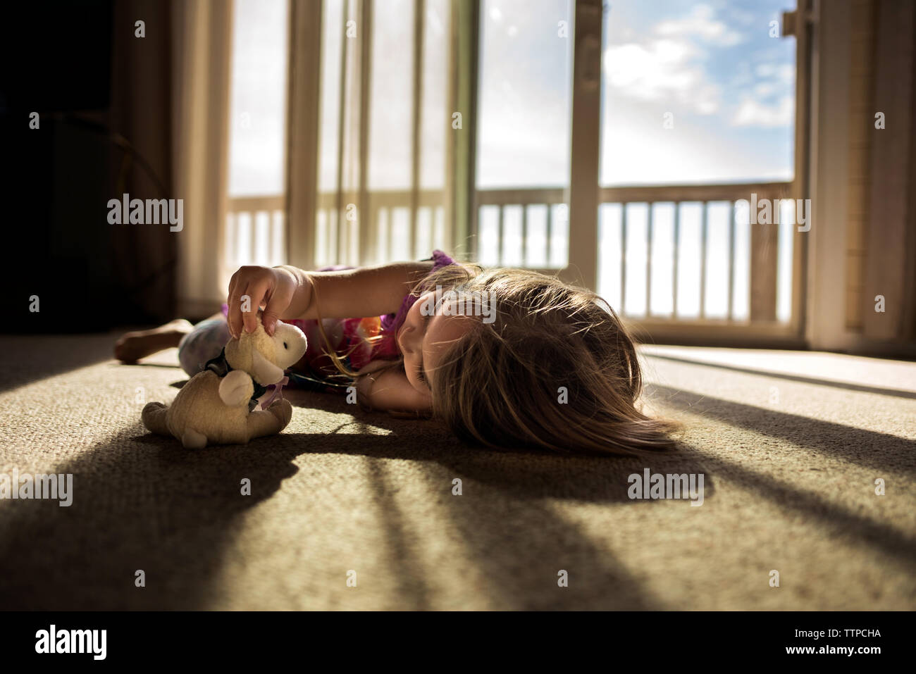 Niña jugando con un mono de peluche en la hermosa luz del sol Foto de stock