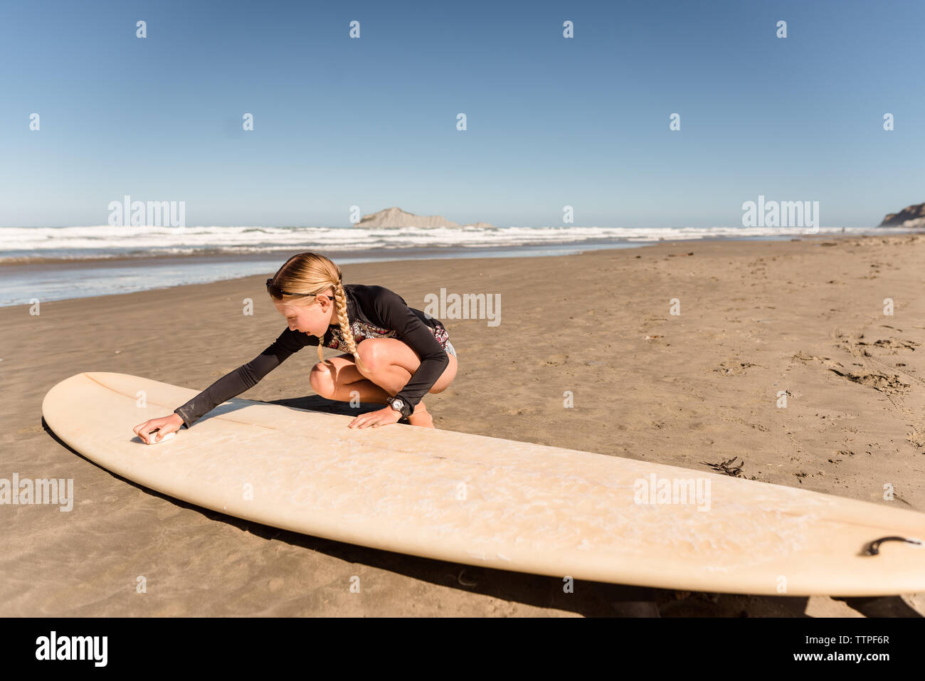 Rubio chica con trenzas encerar una tabla de surf en la playa Fotografía de  stock - Alamy