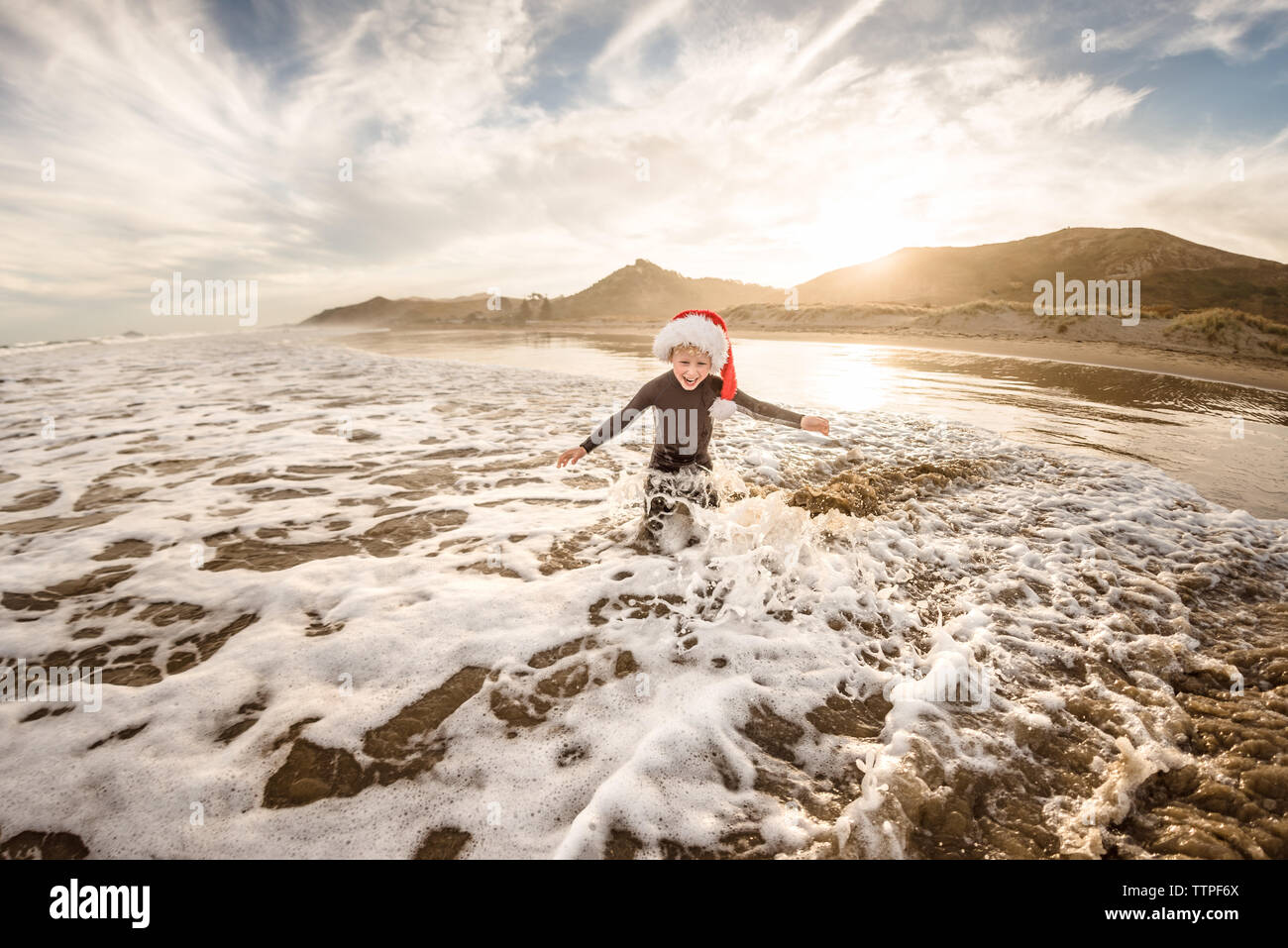 Felices vacaciones niño usando hat jugando en el agua en una playa Foto de stock
