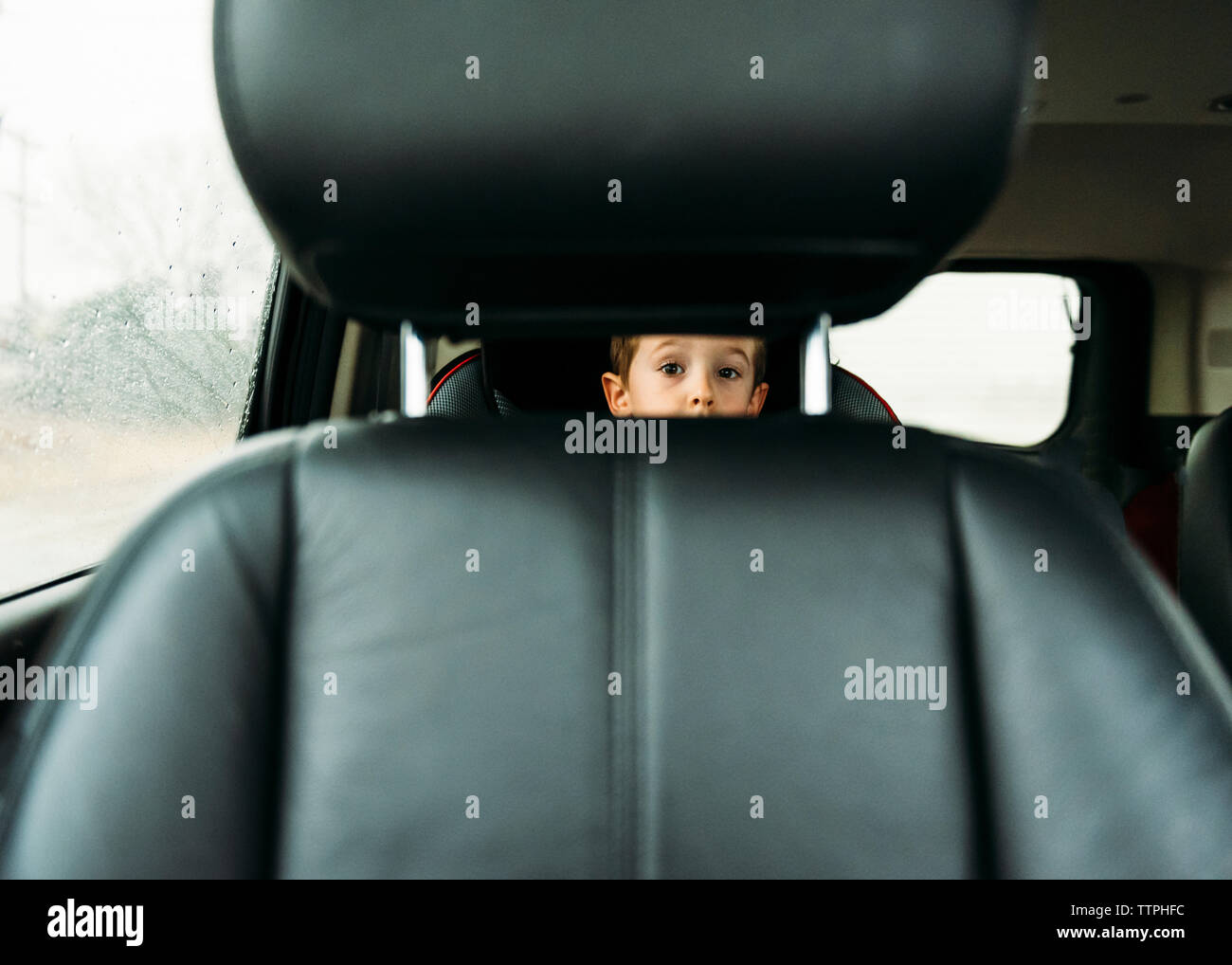 Retrato de niño mirando a través del asiento del vehículo. Foto de stock