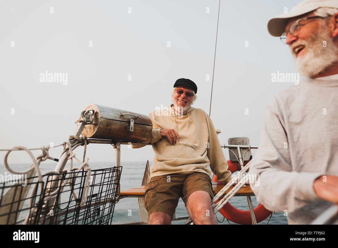 Amigos hablando mientras navegaba en barco contra el cielo claro Foto de stock