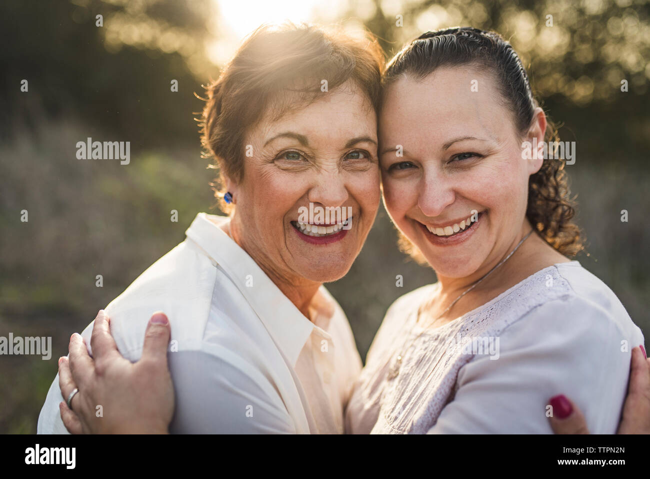 Close Up retrato de madre e hija adulta abrazando y sonriente Foto de stock