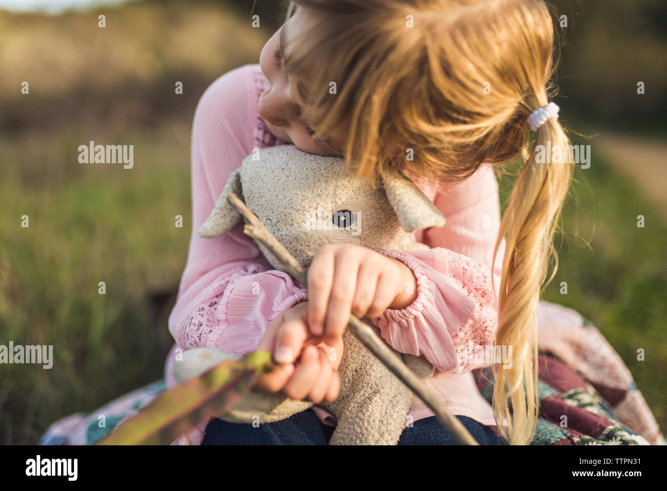 Joven rubia chica sujetando su animal de peluche y caricias Foto de stock