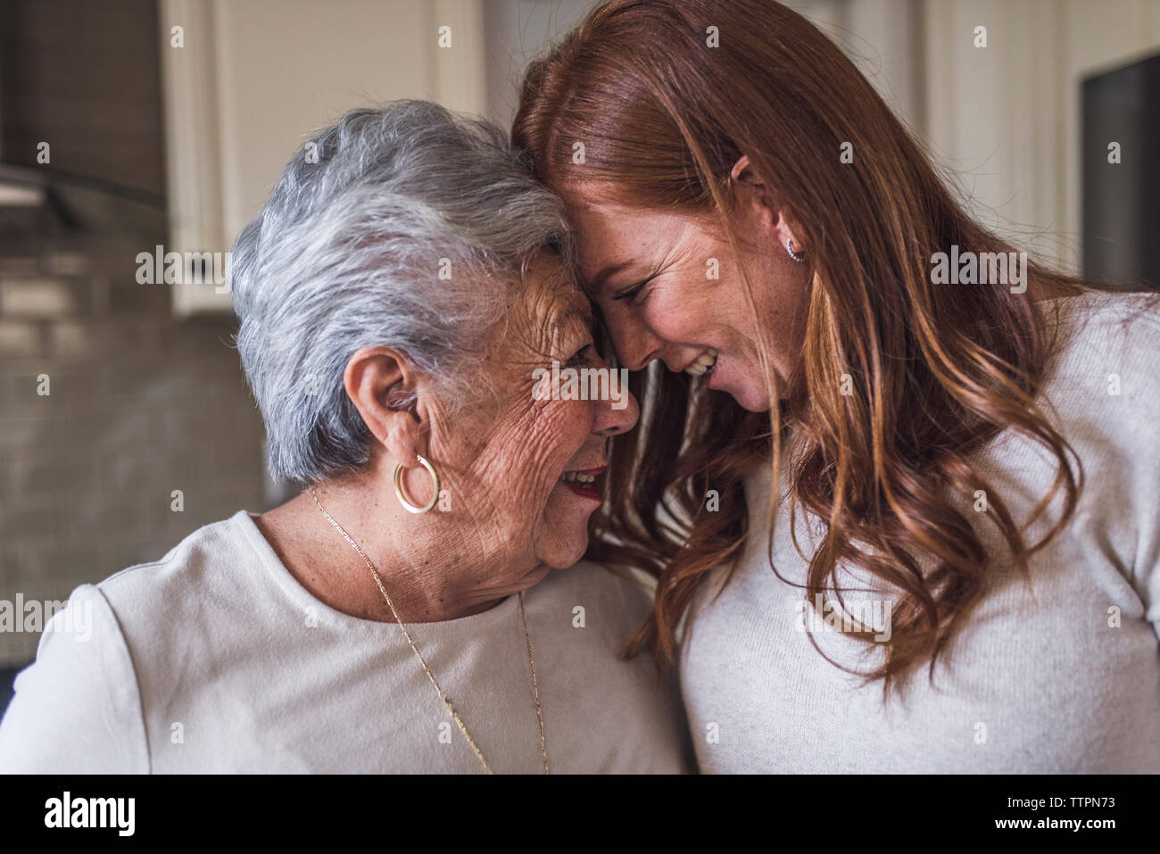 Cerca de la mujer de más edad y adultos nieta tocando frentes Foto de stock