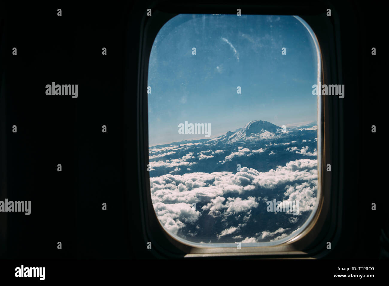 Cielo nublado en medio de montañas nevadas vistos a través de la ventana de avión Foto de stock