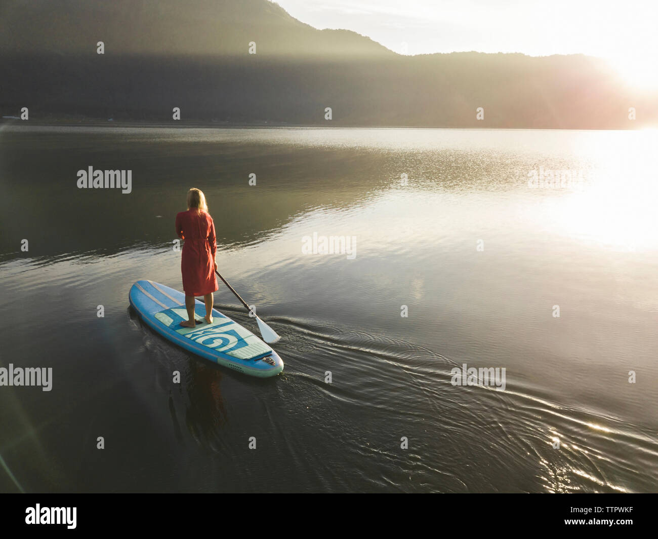 Una hembra paddleboarding sobre un lago al amanecer. Foto de stock