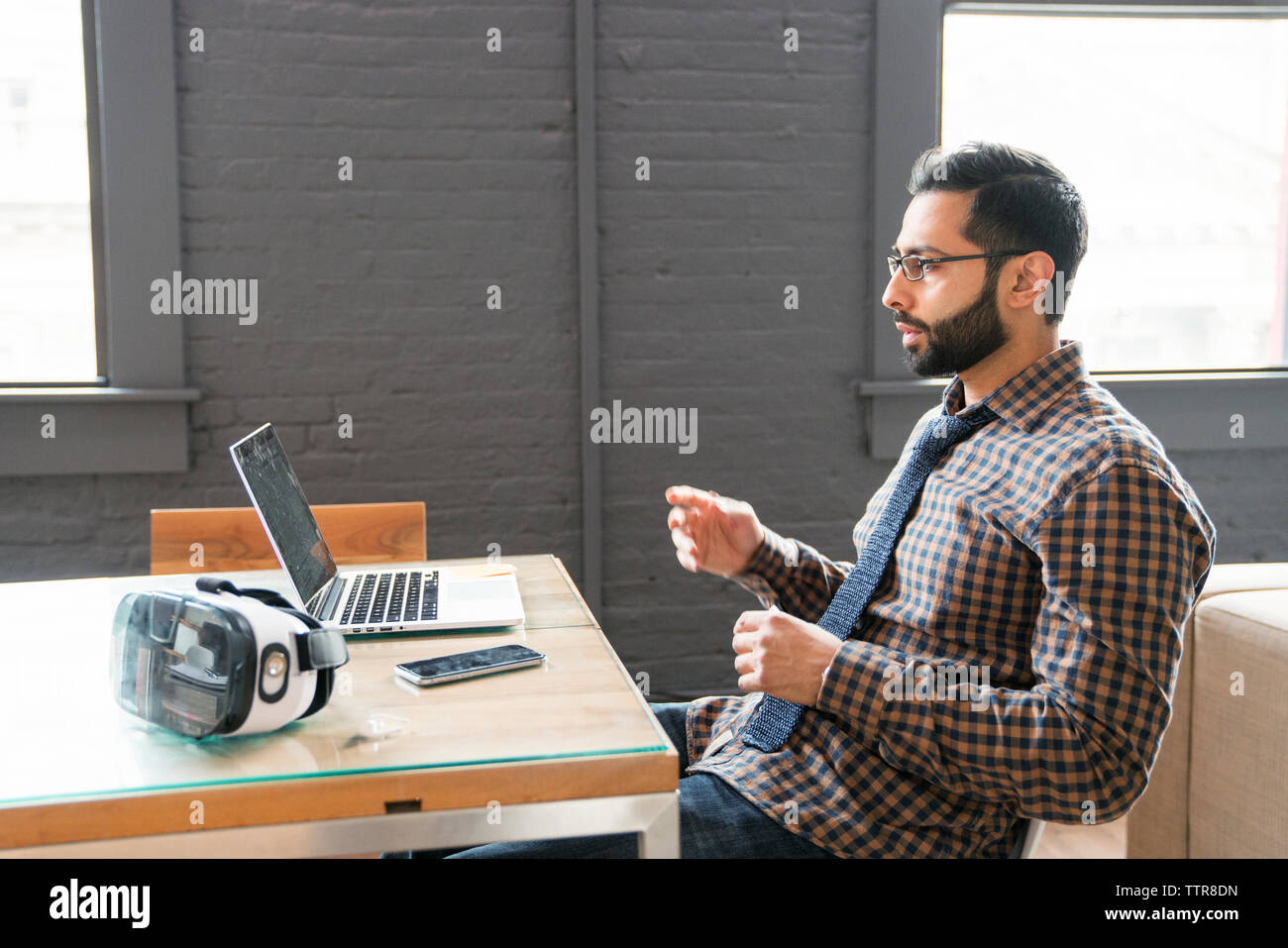 Empresario utilizando equipo portátil mientras está sentado en un escritorio en la oficina Foto de stock