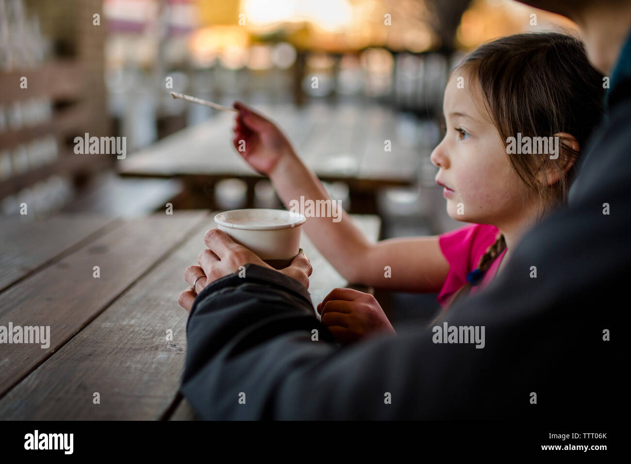 Un niño se sienta con su padre en un café al aire libre al atardecer Foto de stock