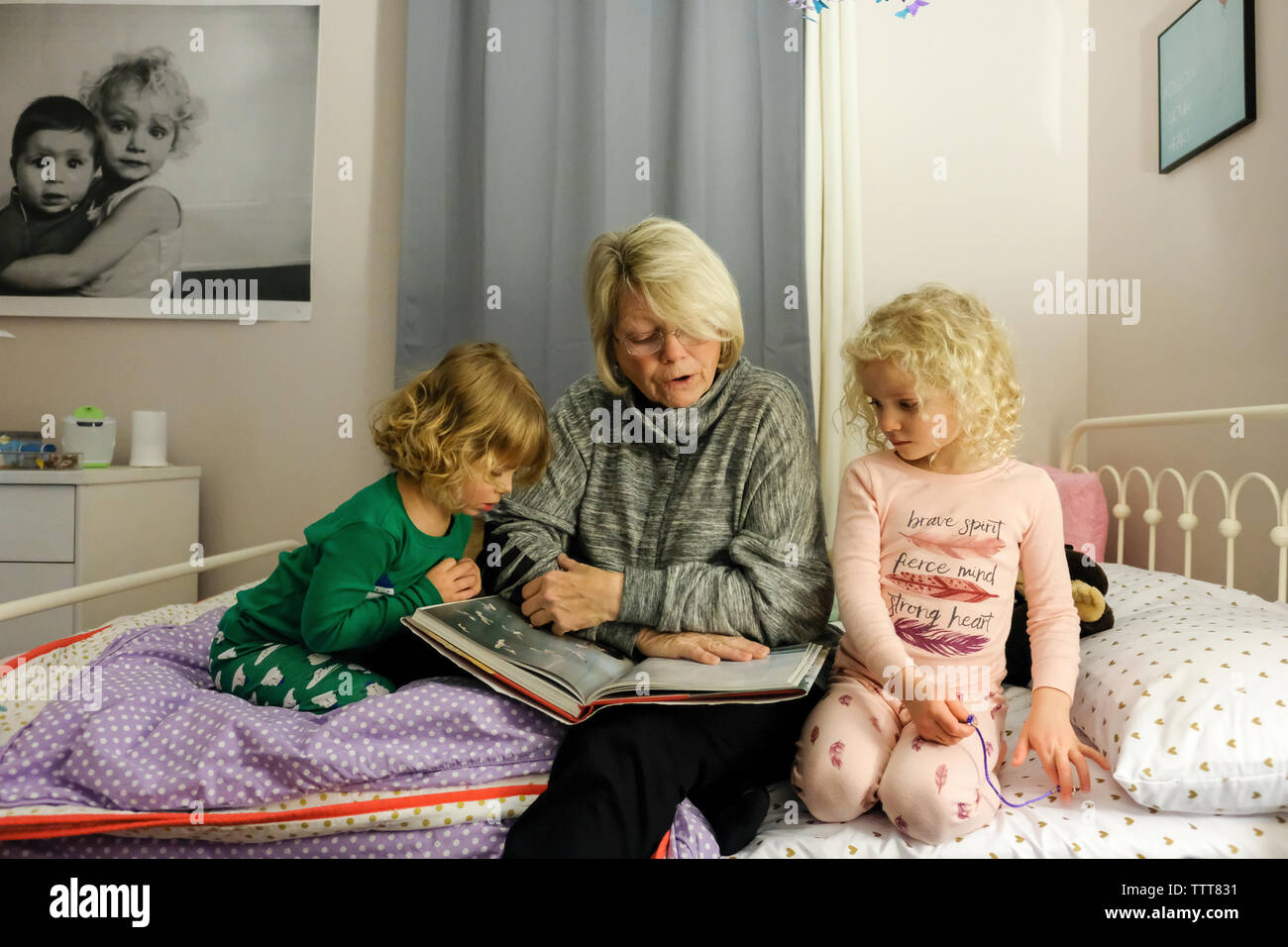 Abuela contar la historia a nietas mientras está sentado en la cama en casa Foto de stock