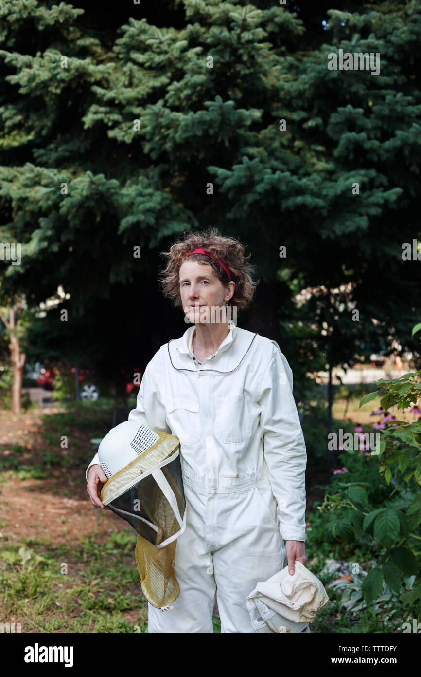 Retrato de seguros altos apicultor vistiendo traje de protección sobre el terreno permanente Foto de stock