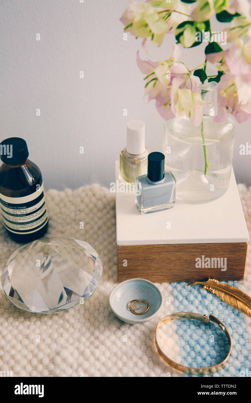 Productos de belleza con joyas y cristal por florero en la mesa Foto de stock