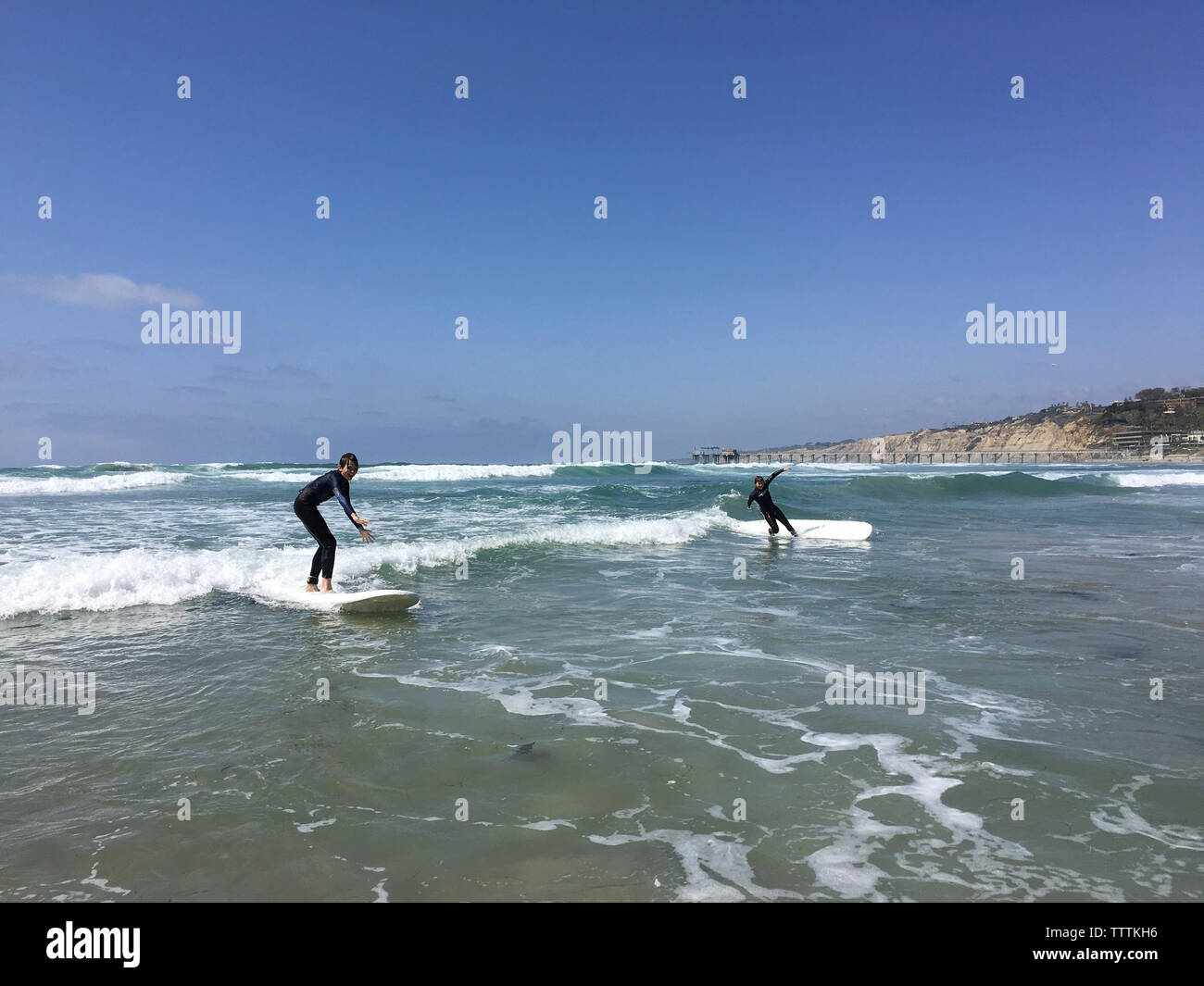 Hermanos despreocupada surf en el mar contra el cielo Foto de stock